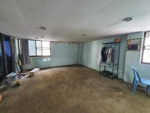 Spacious unfurnished living room with large windows and a worn carpet