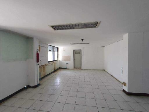 Spacious unfurnished interior of a building with white tiles and natural light