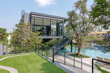 Modern building with large glass windows overlooking a pool and garden