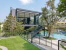 Modern detached studio with full-height glass windows overlooking a pool and garden