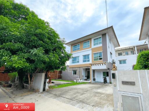 Modern three-story residential building with a spacious front yard and greenery