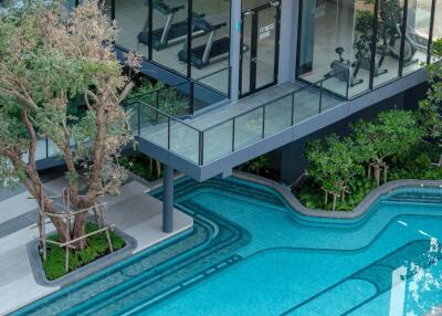 Modern outdoor pool with adjacent gym and lush landscaping