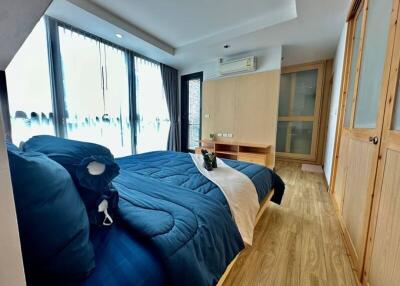 Spacious bedroom with wooden flooring, modern furnishings and large windows