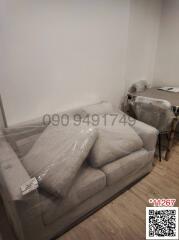 Newly furnished living room with protective plastic coverings on furniture