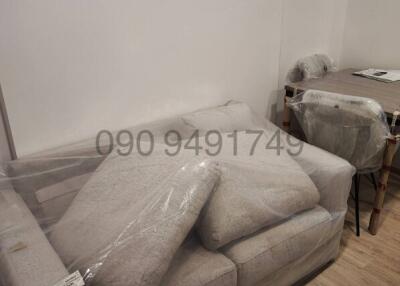 Newly furnished living room with protective plastic coverings on furniture