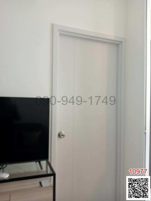 White bedroom door with blurred view of a TV and stand in a modern room