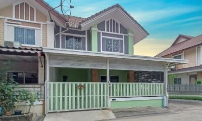 Two-story residential house with green exterior accents and a fenced front yard