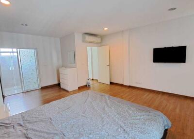 Spacious bedroom with wooden flooring, white walls, and modern furnishings