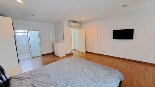 Spacious bedroom with wooden flooring, white walls, and modern furnishings