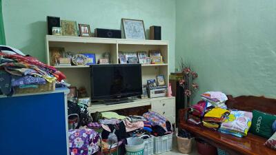 Cluttered living room with a large TV and shelves