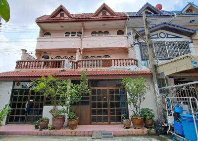 Exterior view of a two-story residential building with a balcony and plants