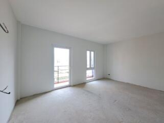 Spacious unfurnished bedroom with large windows and balcony access