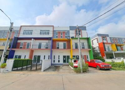 Colorful multi-story residential building facade with parked cars