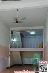 Interior of a building with a mezzanine floor and visible contact number