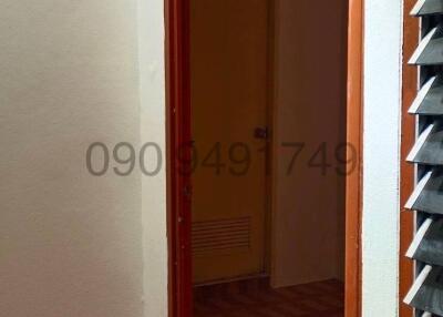 Narrow hallway leading to a room with tiled flooring and storage shelves