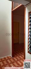 Narrow hallway leading to a room with tiled flooring and storage shelves