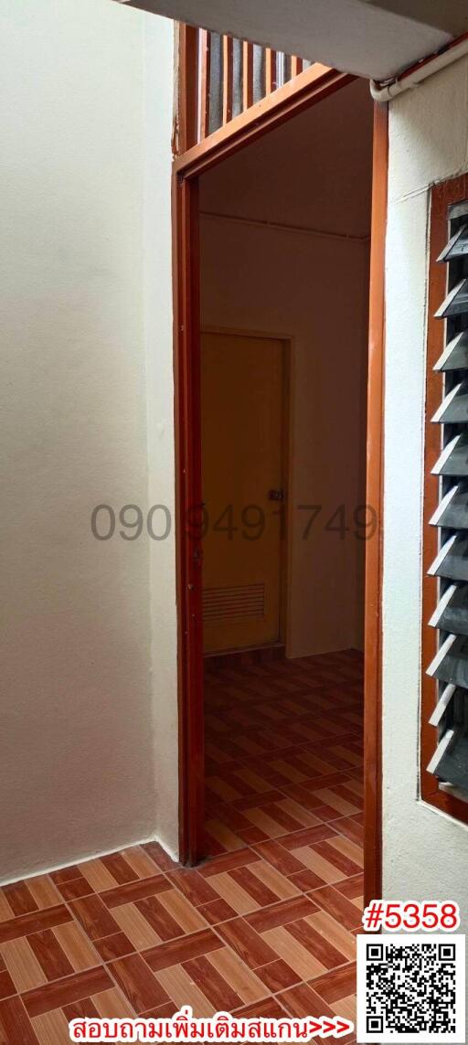 Narrow hallway leading to a room with tiled flooring and storage shelves