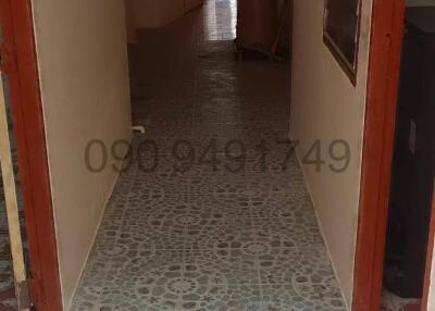 Long tiled corridor with doors to adjacent rooms leading towards a lit area