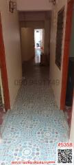 Long tiled corridor with doors to adjacent rooms leading towards a lit area