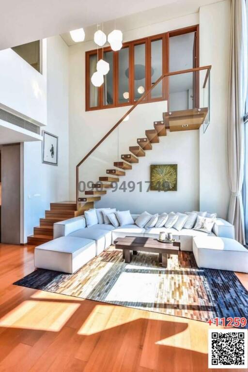 Modern spacious living room with high ceiling and staircase