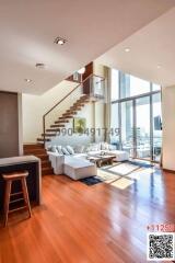 Modern living room interior with large windows, wooden flooring, and a staircase