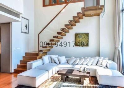 Spacious and well-lit living room with modern staircase and stylish furniture