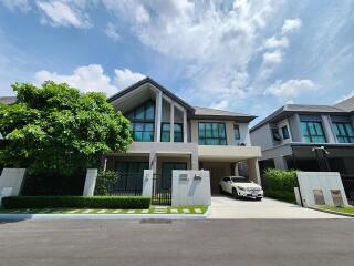 Modern two-story residential home with green landscaping and a parked car