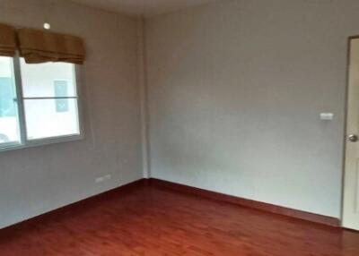 Empty bedroom with hardwood floors and a single window