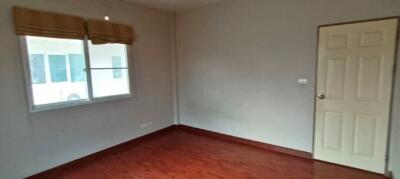 Empty bedroom with hardwood floors and a single window