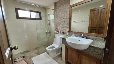 Modern bathroom with walk-in shower, wooden cabinets, and stone countertops