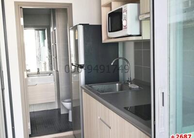 Compact modern kitchen with stainless steel sink, appliances and bathroom entrance