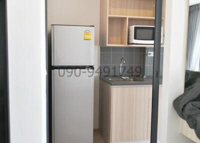 Compact modern kitchen with wooden cabinets and grey refrigerator