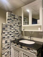 Modern bathroom with patterned tile walls and granite sink countertop