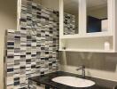 Modern bathroom with patterned tile walls and granite sink countertop