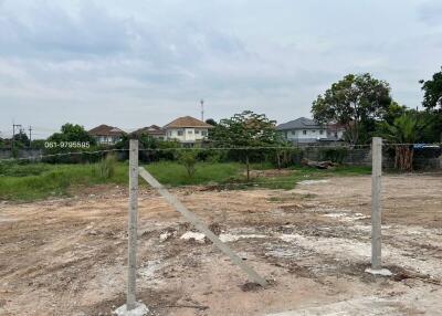 Empty land plot available for construction with nearby houses in background