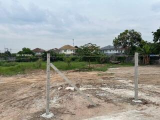 Empty land plot available for construction with nearby houses in background