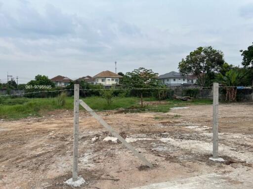 Empty land plot available for construction with nearby houses in background