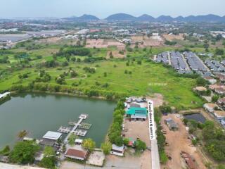 Aerial view of a residential area with a lake, houses, and open land