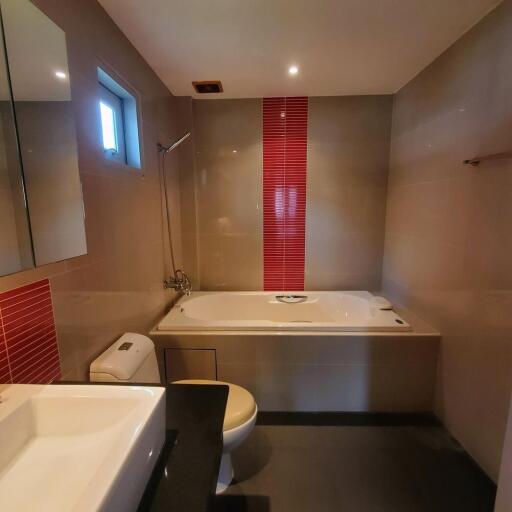 Modern bathroom with bathtub and red accent tiles