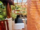 Cozy balcony with wooden flooring and modern brick walls surrounded by green plants under a pergola