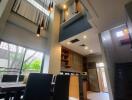 High ceiling dining area with modern lighting and adjacent kitchen