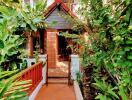 Entrance of a cozy house surrounded by lush greenery with a terracotta tiled pathway