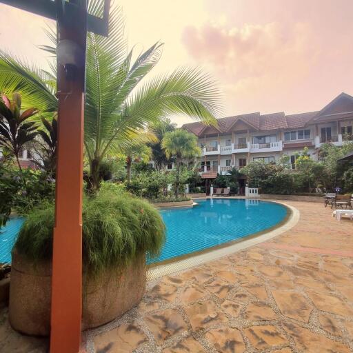 Tropical resort-style outdoor pool area with palm trees and sun loungers