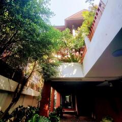 Inviting exterior view of a house with lush greenery and covered parking space