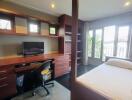 Spacious bedroom with a work area, dark wood furnishings, and balcony access