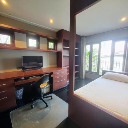 Spacious bedroom with a work area, dark wood furnishings, and balcony access