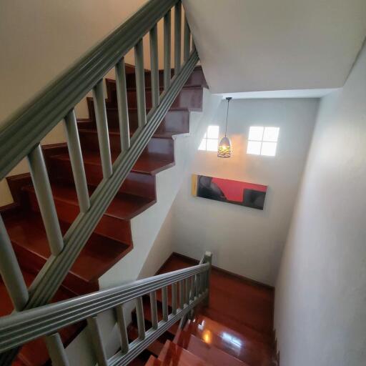 Wooden staircase with polished handrails and white walls in a modern home