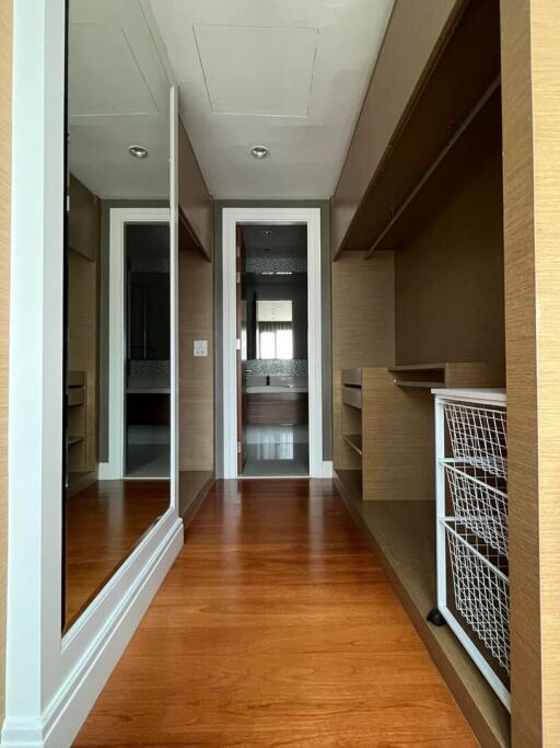 Wooden floored hallway with built-in storage leading to a bathroom