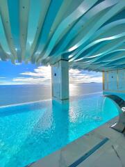 Luxurious outdoor infinity pool with a stunning ocean view and unique wave-shaped ceiling