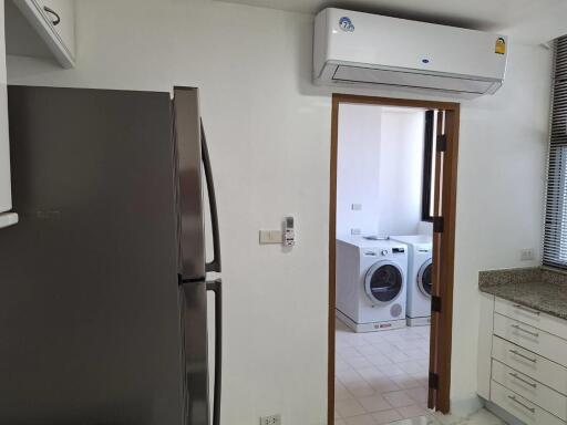 Modern kitchen with stainless steel appliances and washer-dryer setup